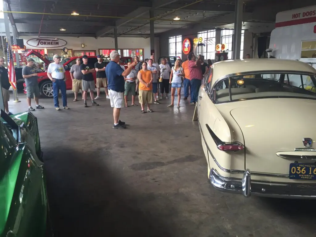 group of visitors gather near a car inside the museum