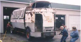 Two people pulling the Futurliner with a rope to guide it into a barn