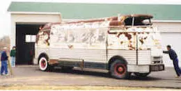 A person helping to guide the rusted Futurliner backwards into a barn