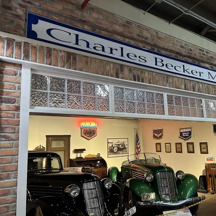 Two cars sit in a replica storefront of the Auburn Automobile Dealership