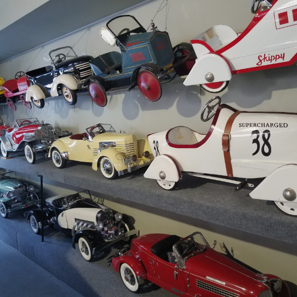 A wall of pedal cars on display