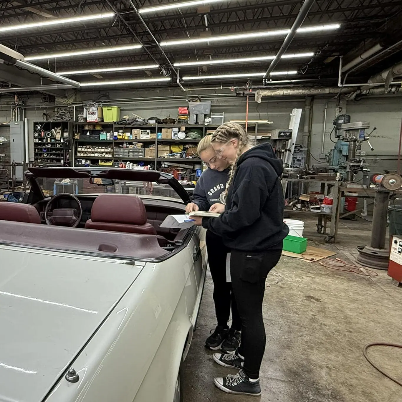 Two youth volunteers read instructions on a servicing a vehicle